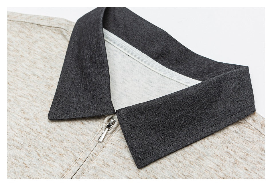 Close-up of a dark charcoal collar and silver zipper on a beige marled garment.