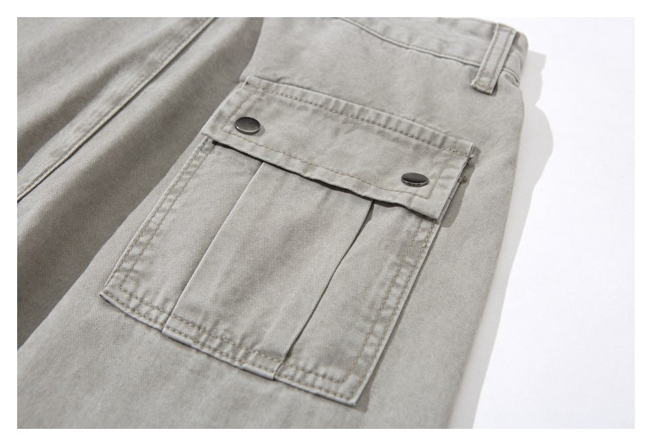 Close-up of a light gray-beige cargo pocket with a two-button flap on the trousers.