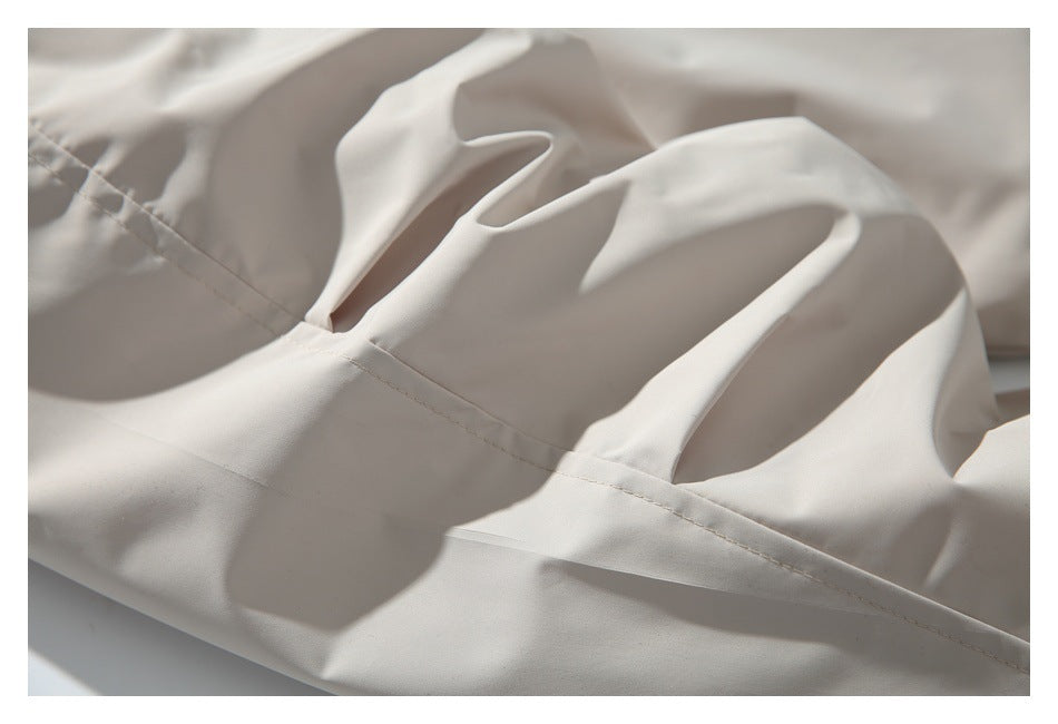 Close-up of stitching and folded fabric on a light beige garment.
