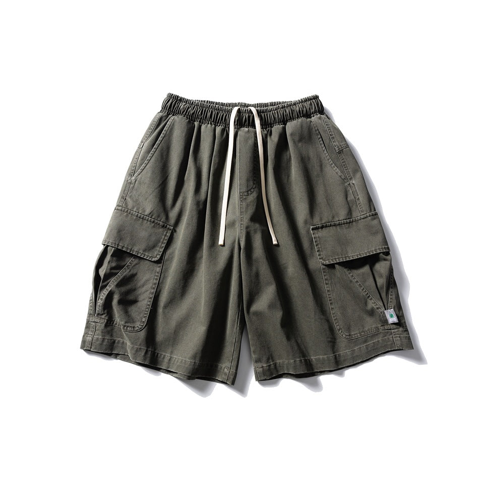 Green cargo shorts flat lay with elastic drawstring waist and large flap pockets on both legs