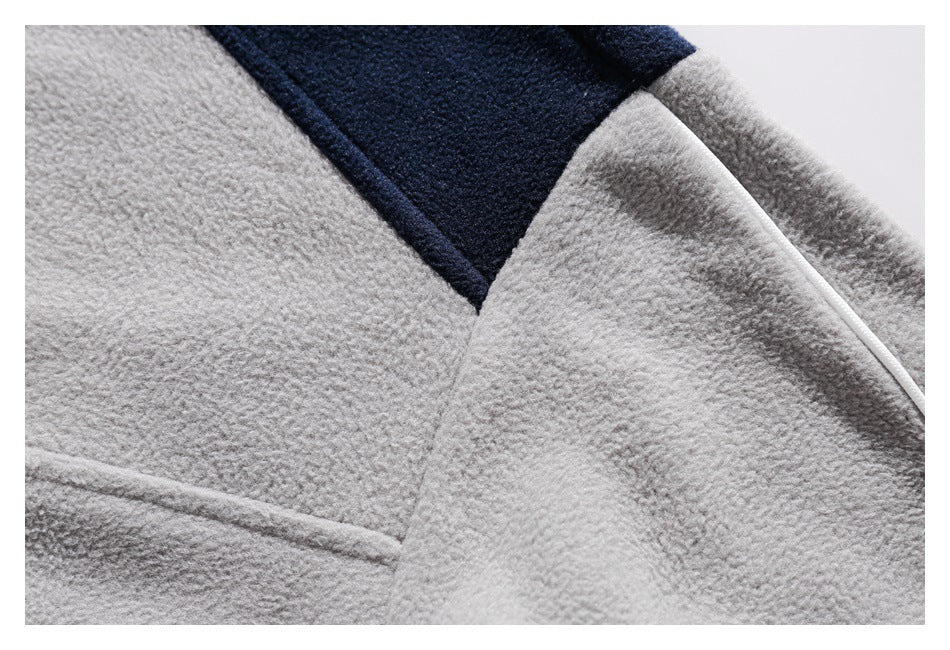 Close-up of light gray fleece panels, navy shoulder color blocking, and a narrow light trim.