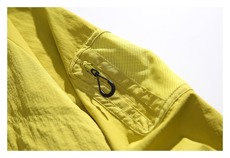 Close-up of a yellow jacket sleeve with a mesh panel, stitched trim, and a black hook attached by a cord.