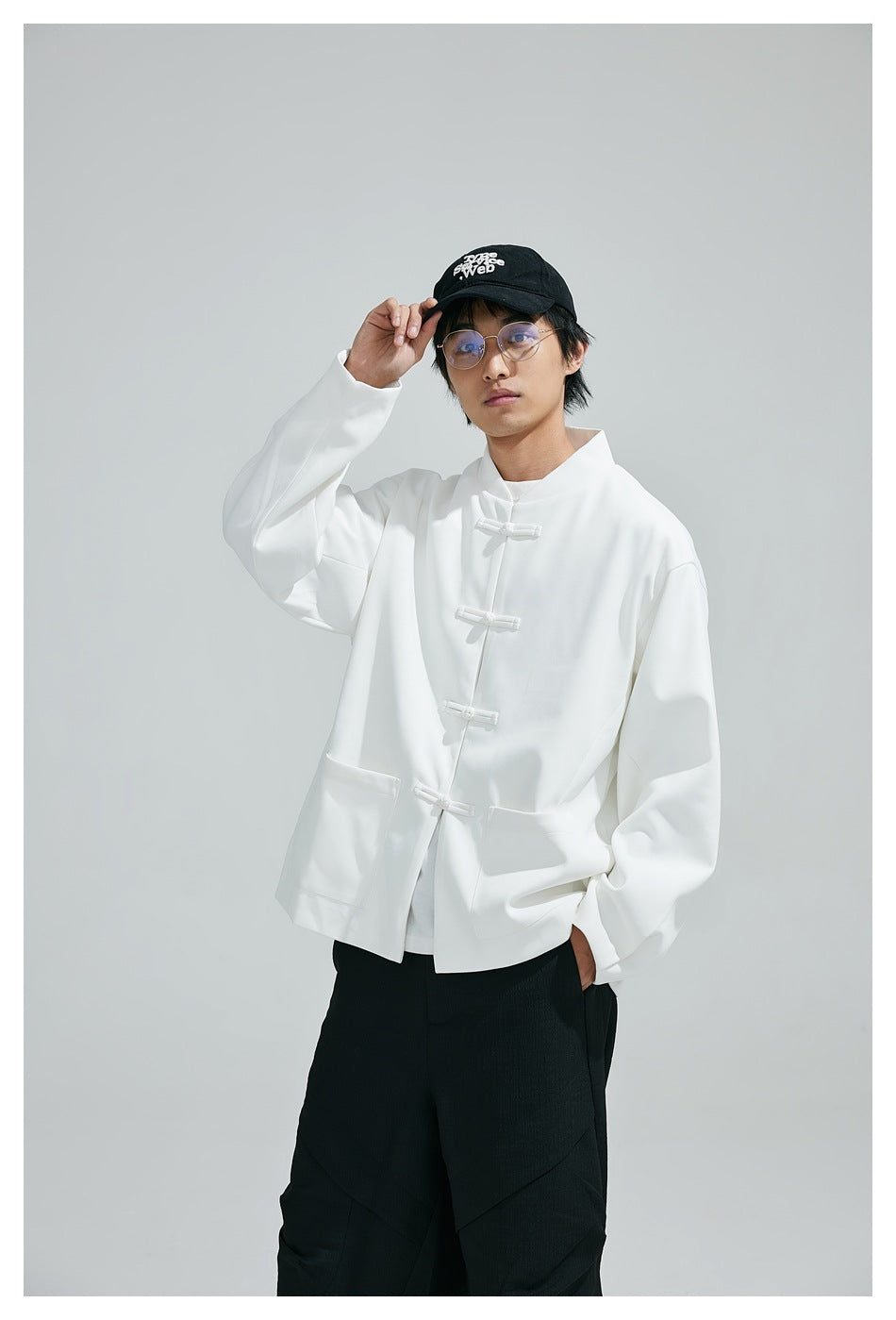Model wearing a white frog-button jacket with front pockets and black trousers.