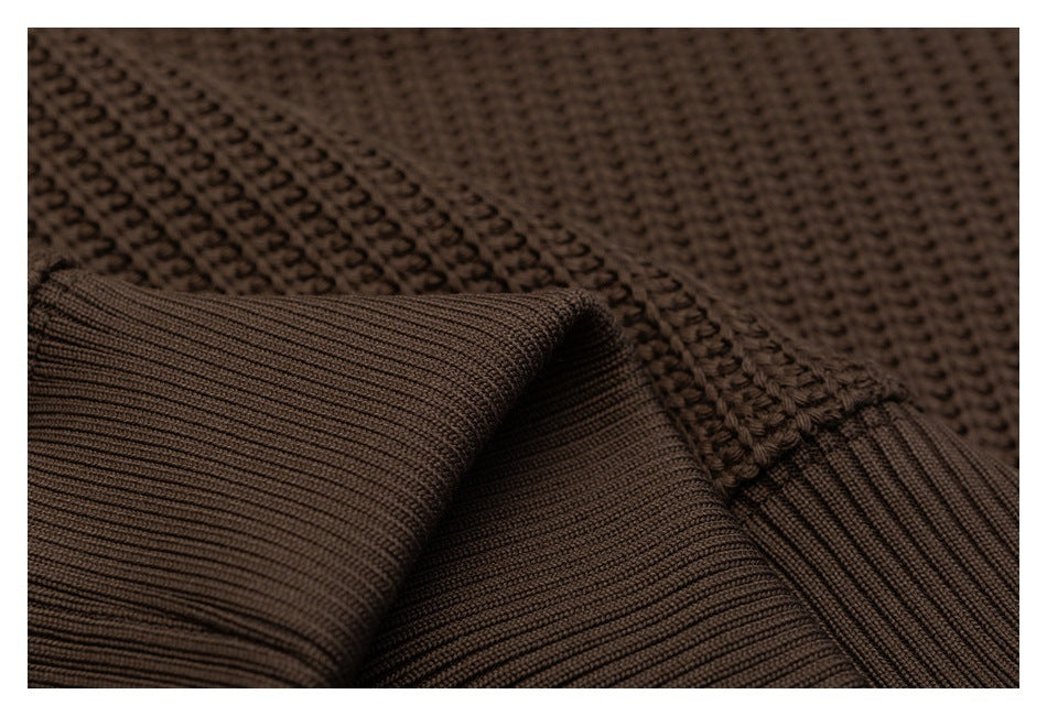 Close-up of dark brown knit fabric with a folded ribbed cuff and textured stitching.
