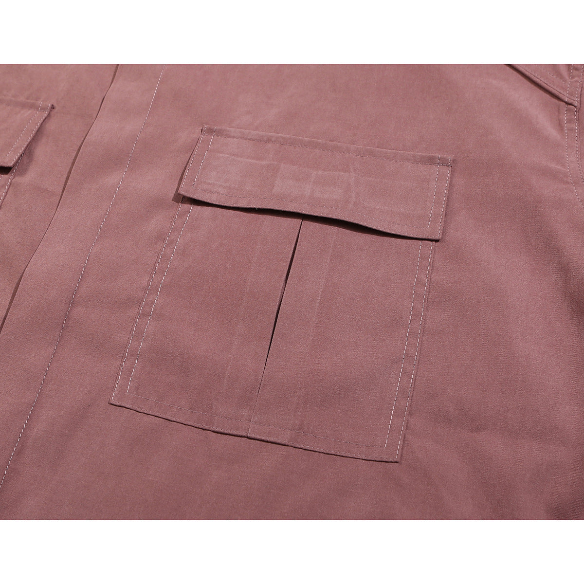 Close-up of a dusty mauve shirt’s large stitched pocket and flap, with part of another pocket visible at the edge.