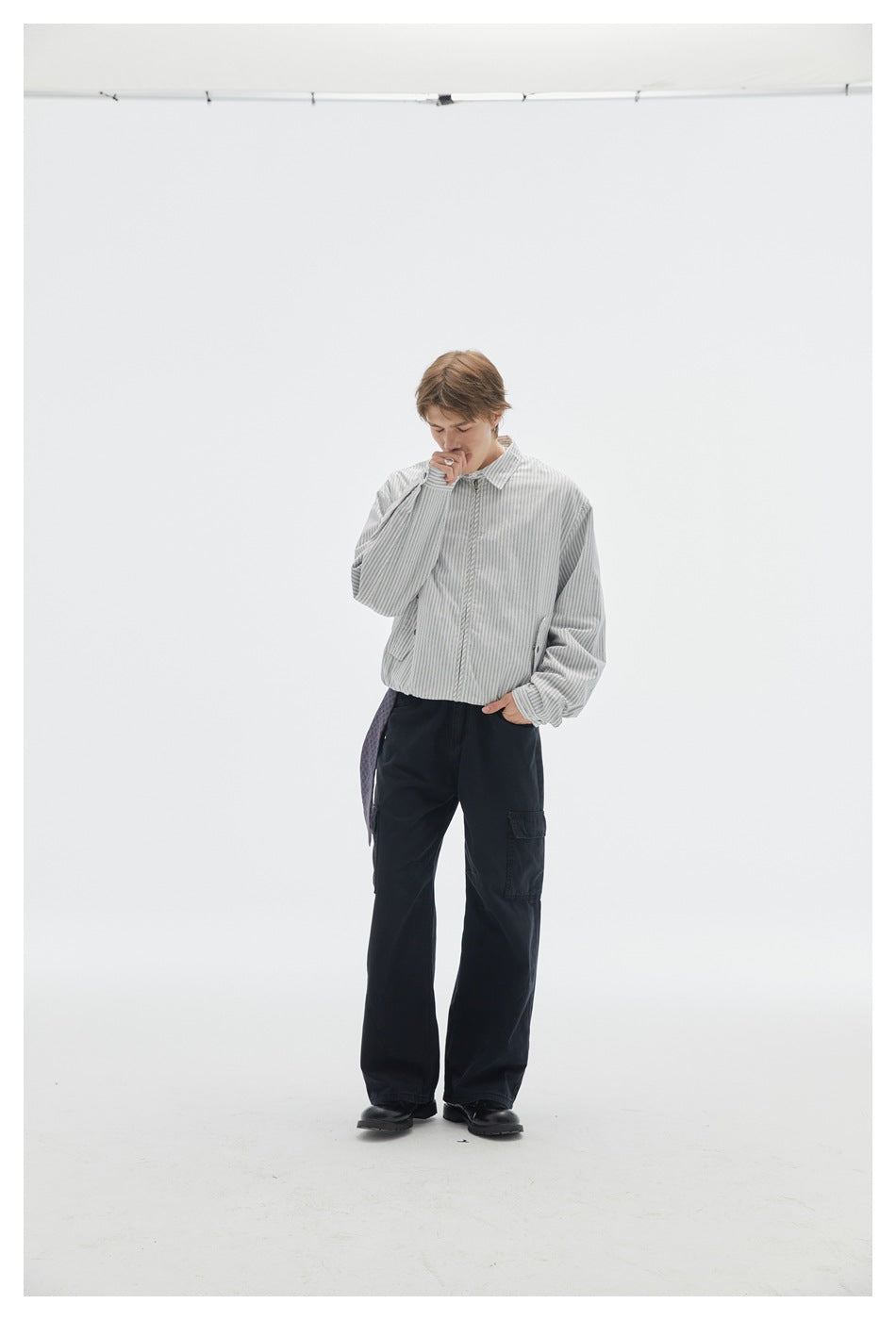Model facing forward in a light gray pinstriped zip jacket and black cargo pants.