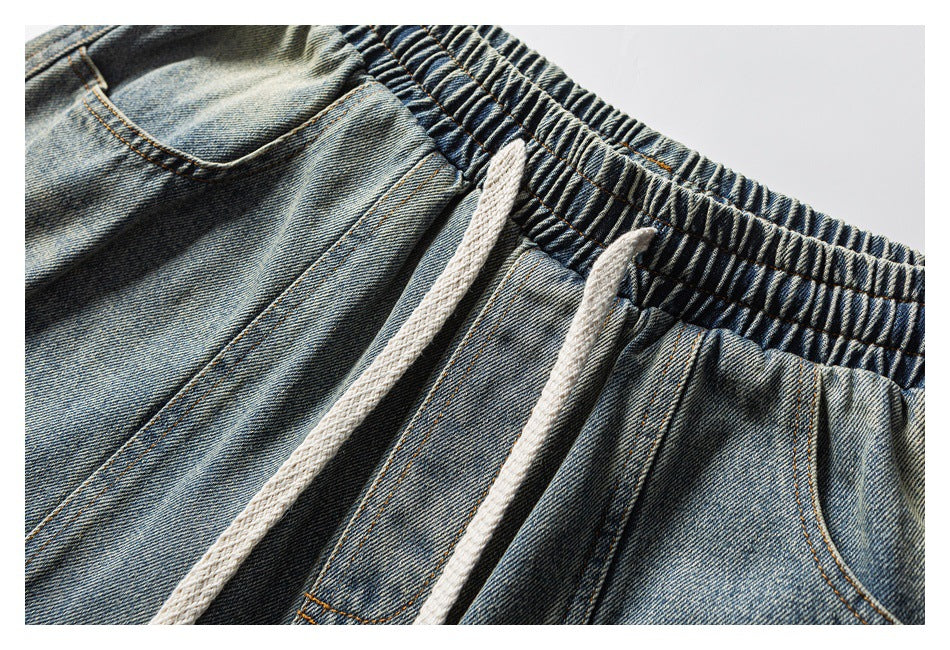 Close-up of blue denim shorts with an elastic waistband, white drawstrings and front pockets.