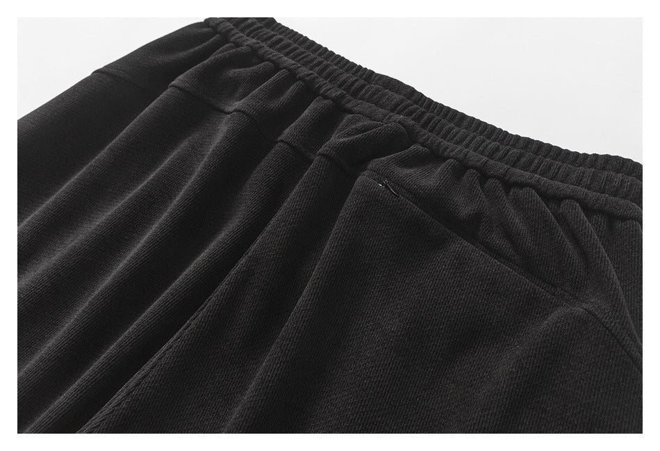 Close-up of black joggers showing the gathered elastic waistband and front pocket.
