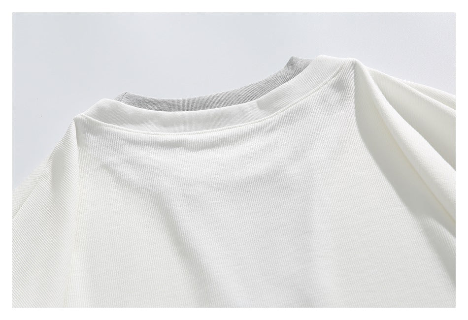 Close-up of the plain white ribbed garment back and neckline, with a gray layer peeking above the collar.