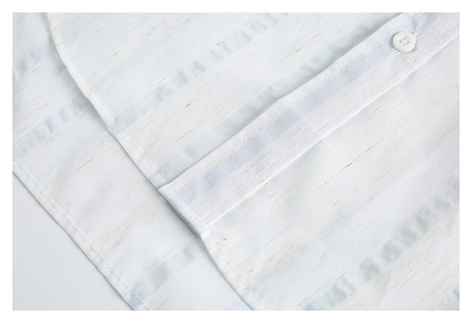 Close-up of the white shirt's button placket and stitching, with subtle tan streaks and pale blue accents.