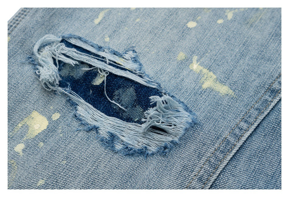 Close-up of a large frayed rip with exposed dark denim on pale blue jeans, surrounded by distressed marks.