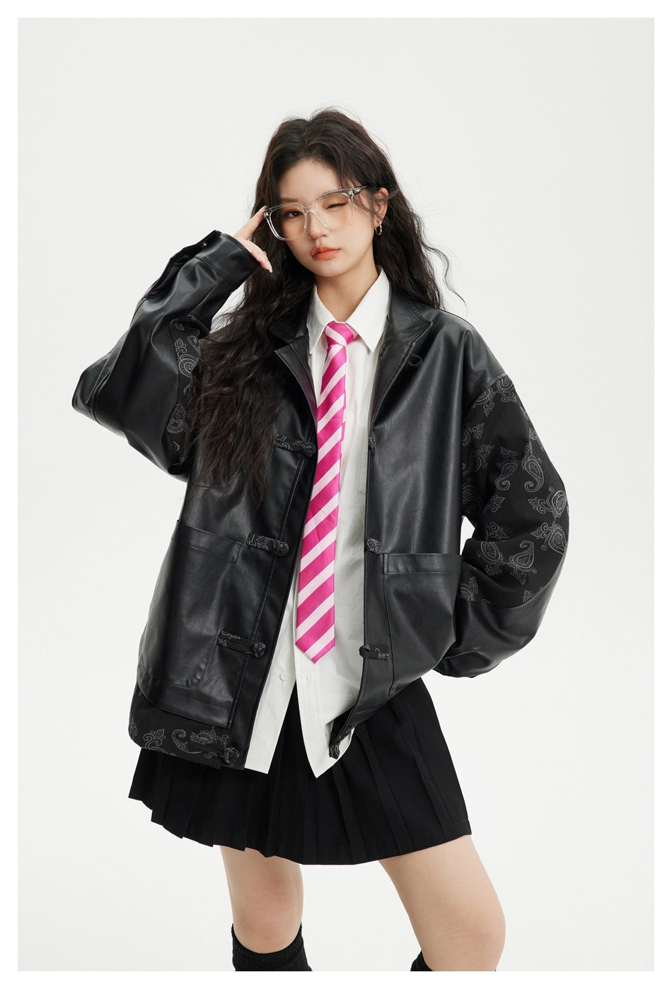 Model posing in an oversized black paisley-sleeve jacket over a white shirt and pink striped tie.