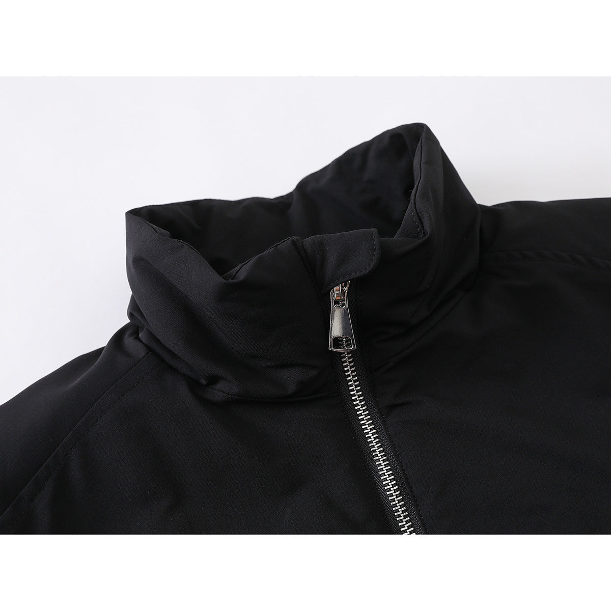 Close-up of a black jacket’s tall collar and silver front zipper.