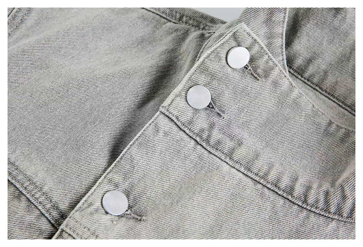 Close-up of a pale gray denim strap with three round silver buttons and stitched seams.