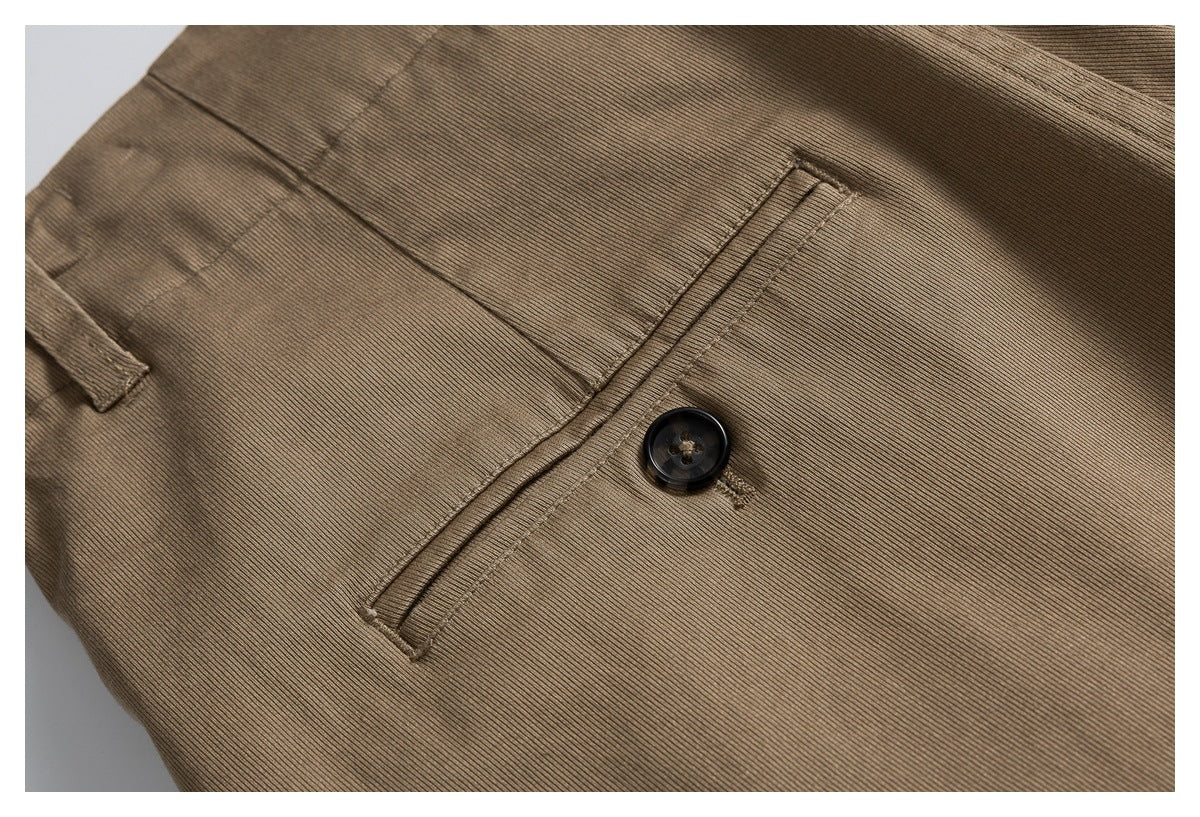 Close-up of a brown trouser welt pocket with a dark button and stitched edges.