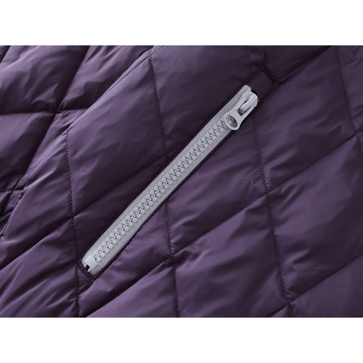 Close-up of a diagonal light-colored pocket zipper on purple diamond-quilted jacket fabric.
