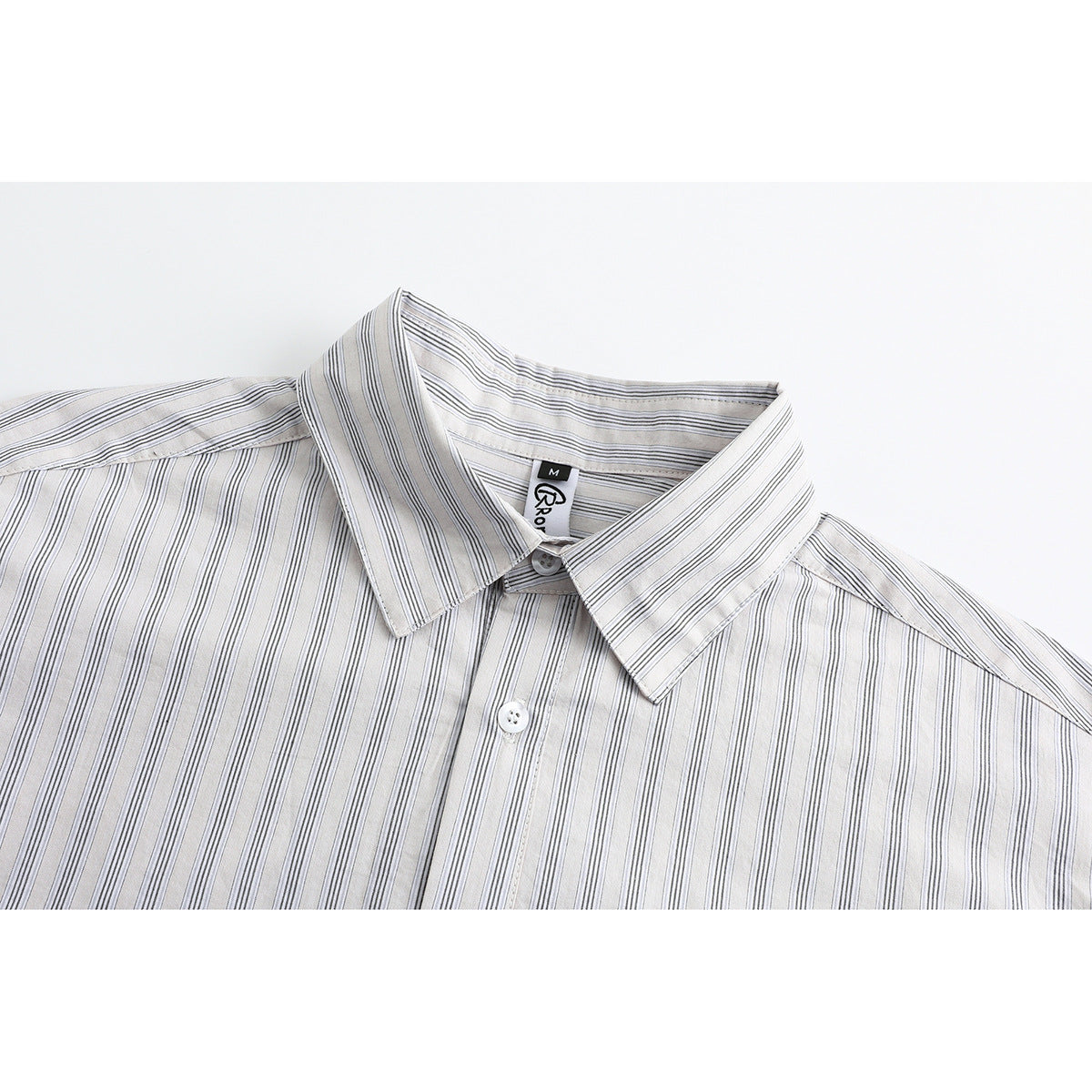Close-up of a white shirt collar and button placket with thin gray vertical stripes and a visible neck label.