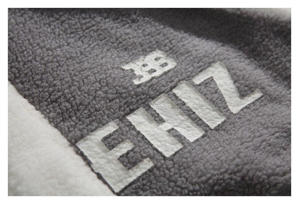 Close-up of white lettering on the gray textured jacket fabric, bordered by a cream panel.