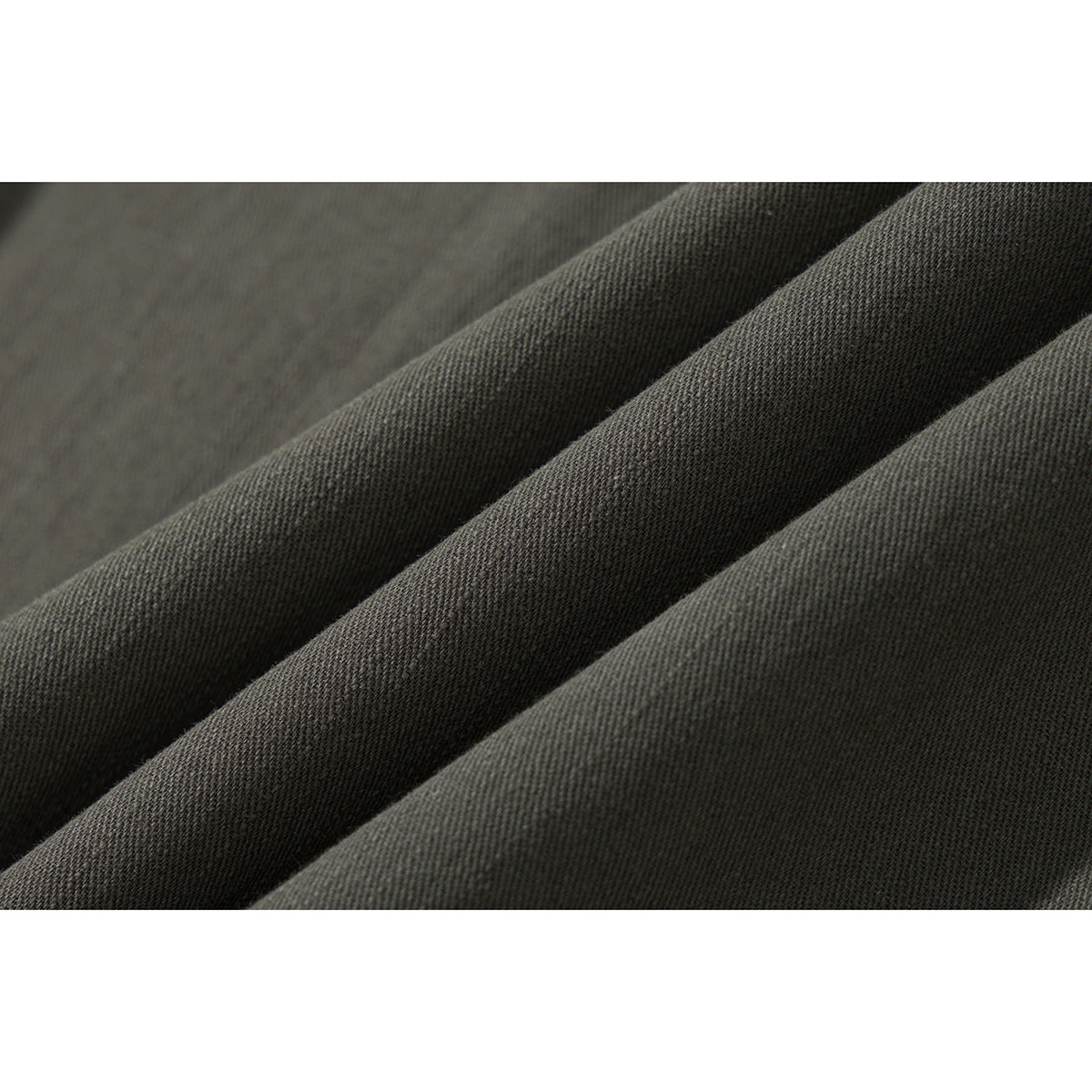 Macro view of the olive-gray shirt fabric arranged in soft diagonal folds.