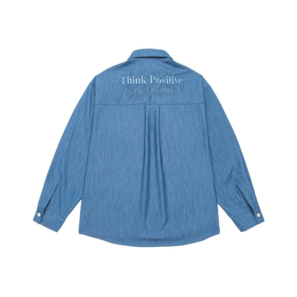 Back view of a blue long-sleeve button-up shirt with white “Think Positive / Be Positive” embroidery across the shoulders.