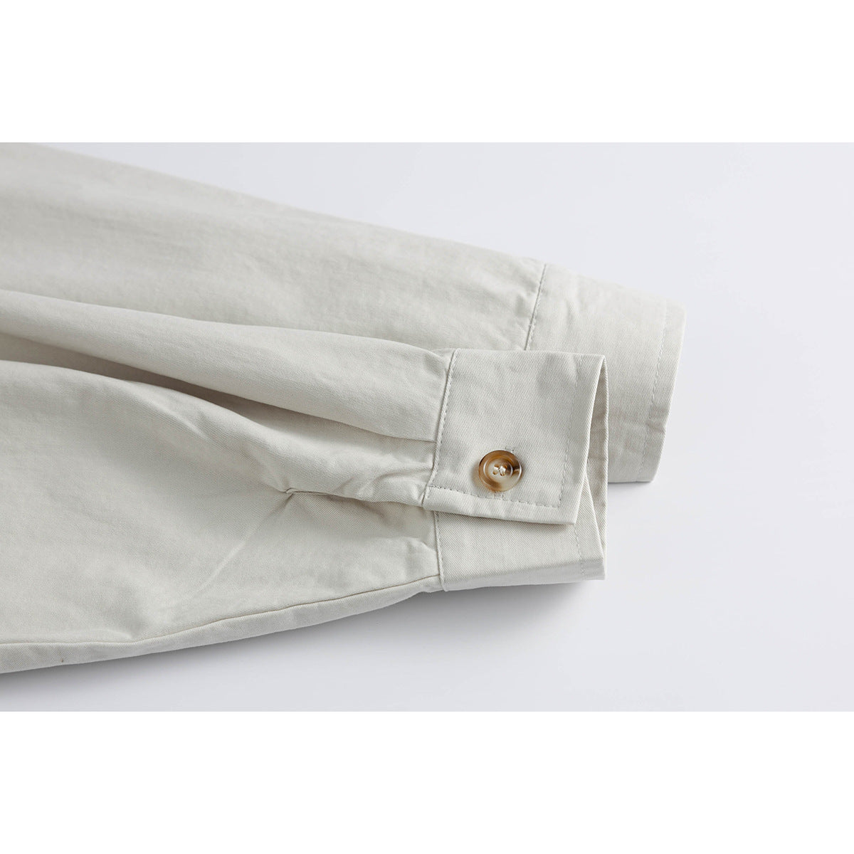 Close-up of an off-white shirt sleeve cuff with a tan button.