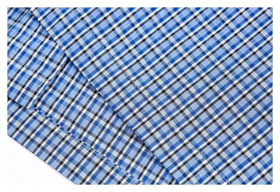 Close-up of blue, white and black plaid fabric with overlapping garment panels and stitching.