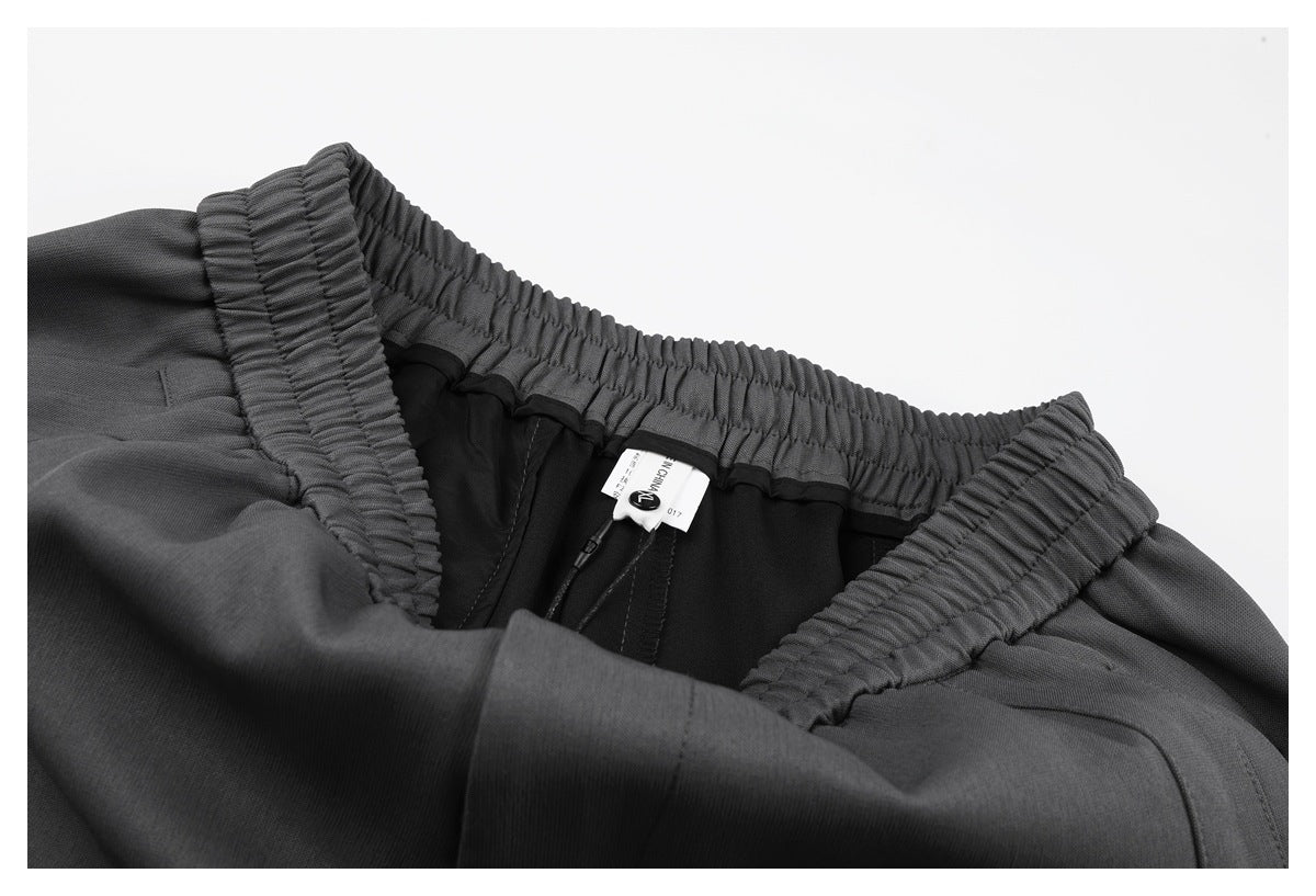 Inside view of charcoal gray pants showing the elastic waistband, lining, and sewn-in label.