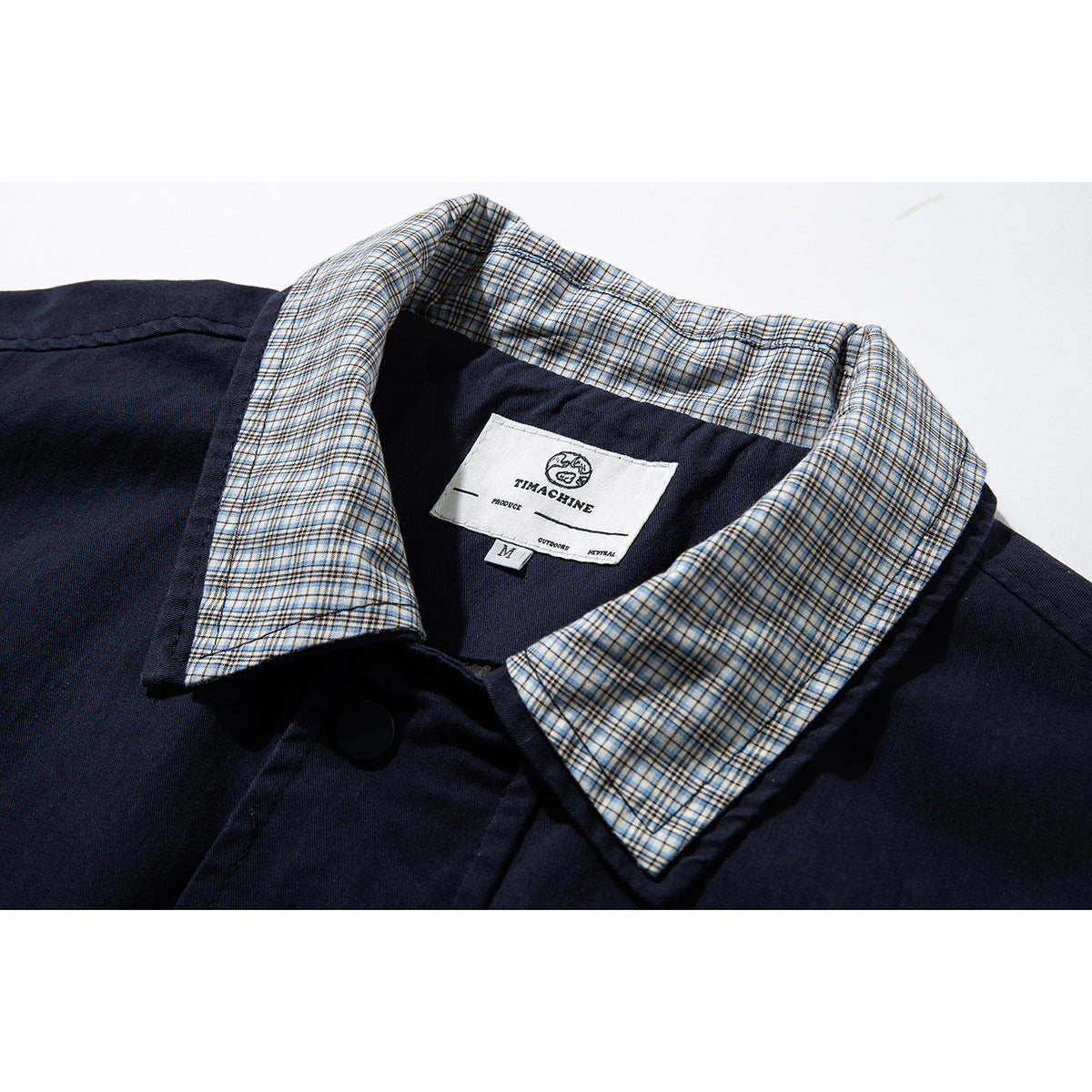 Close-up of a navy jacket with a beige-and-blue plaid collar lining and a sewn-in neck label.