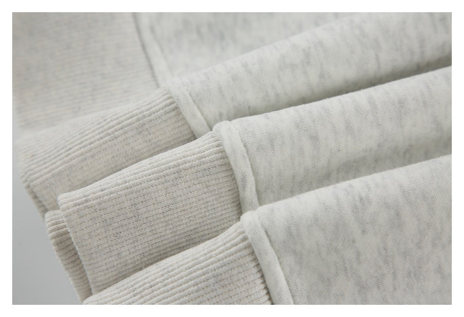 Close-up of the ribbed cuff and sleeve on a light gray marled shirt.