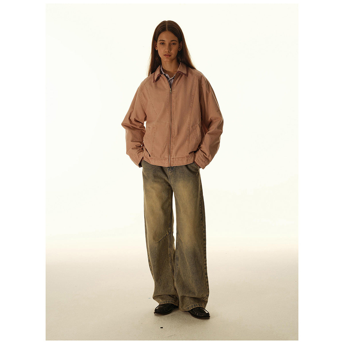 Woman models a dusty rose zip-front jacket with a pointed collar and angled pockets, paired with wide-leg olive jeans.