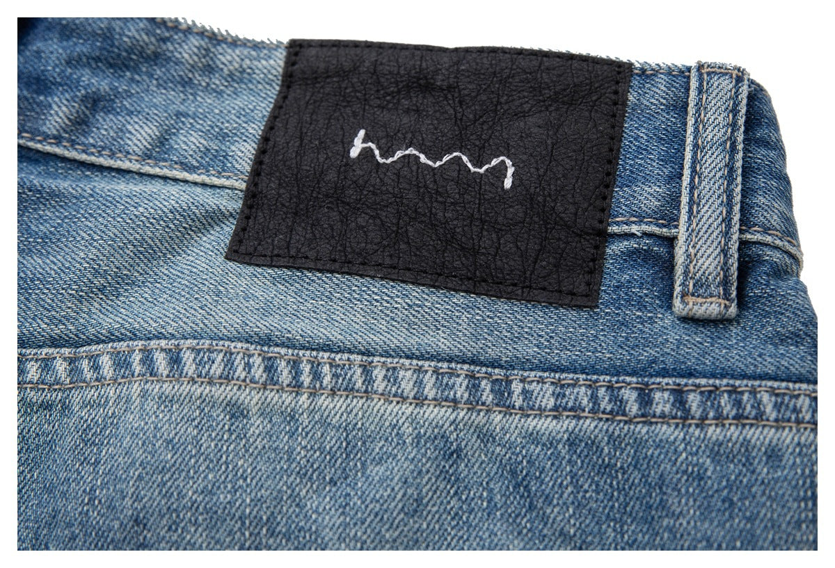 Close-up of a black patch with a white squiggle on the waistband of blue jeans.