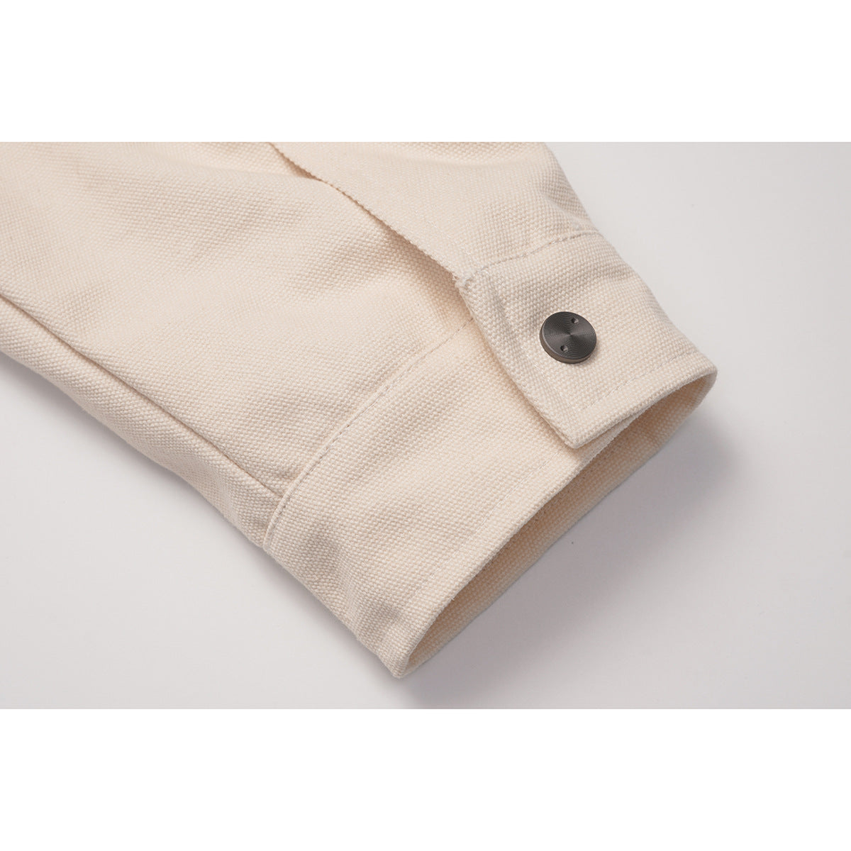 Close-up of a cream jacket sleeve cuff with a dark button and visible stitching.