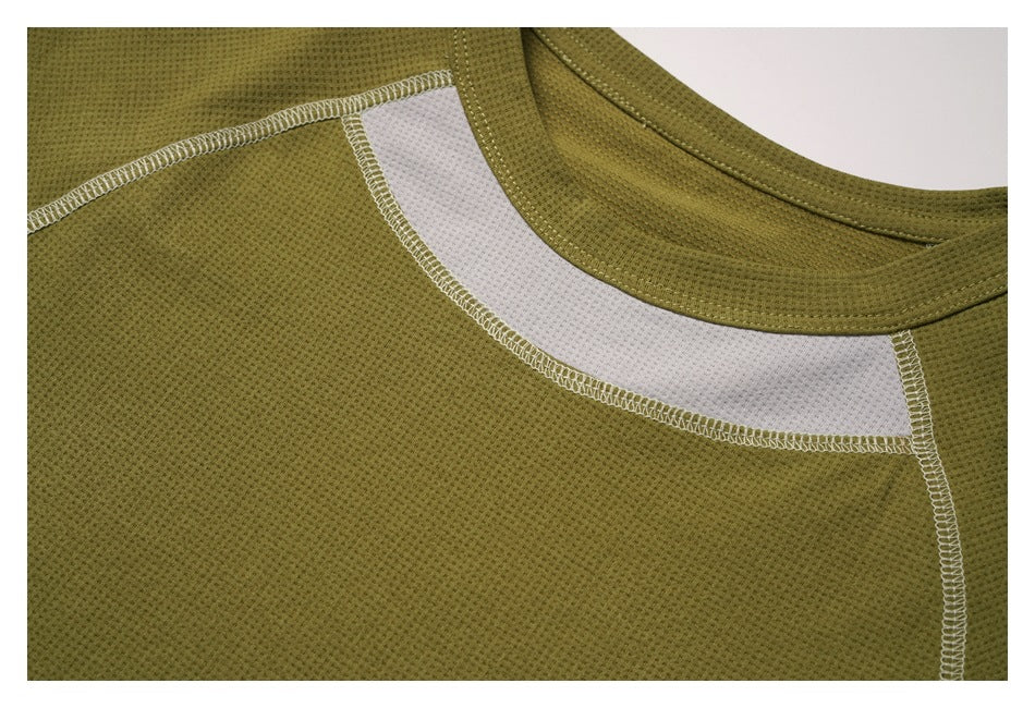Close-up of an olive-green garment neckline with a curved white contrast panel and overlocked stitching.