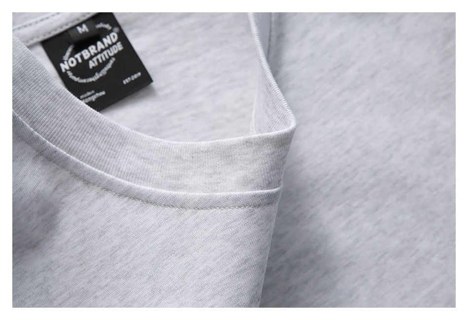 Close-up of the light gray neckline with a black sewn-in label reading “NOTBRAND ATTITUDE.”