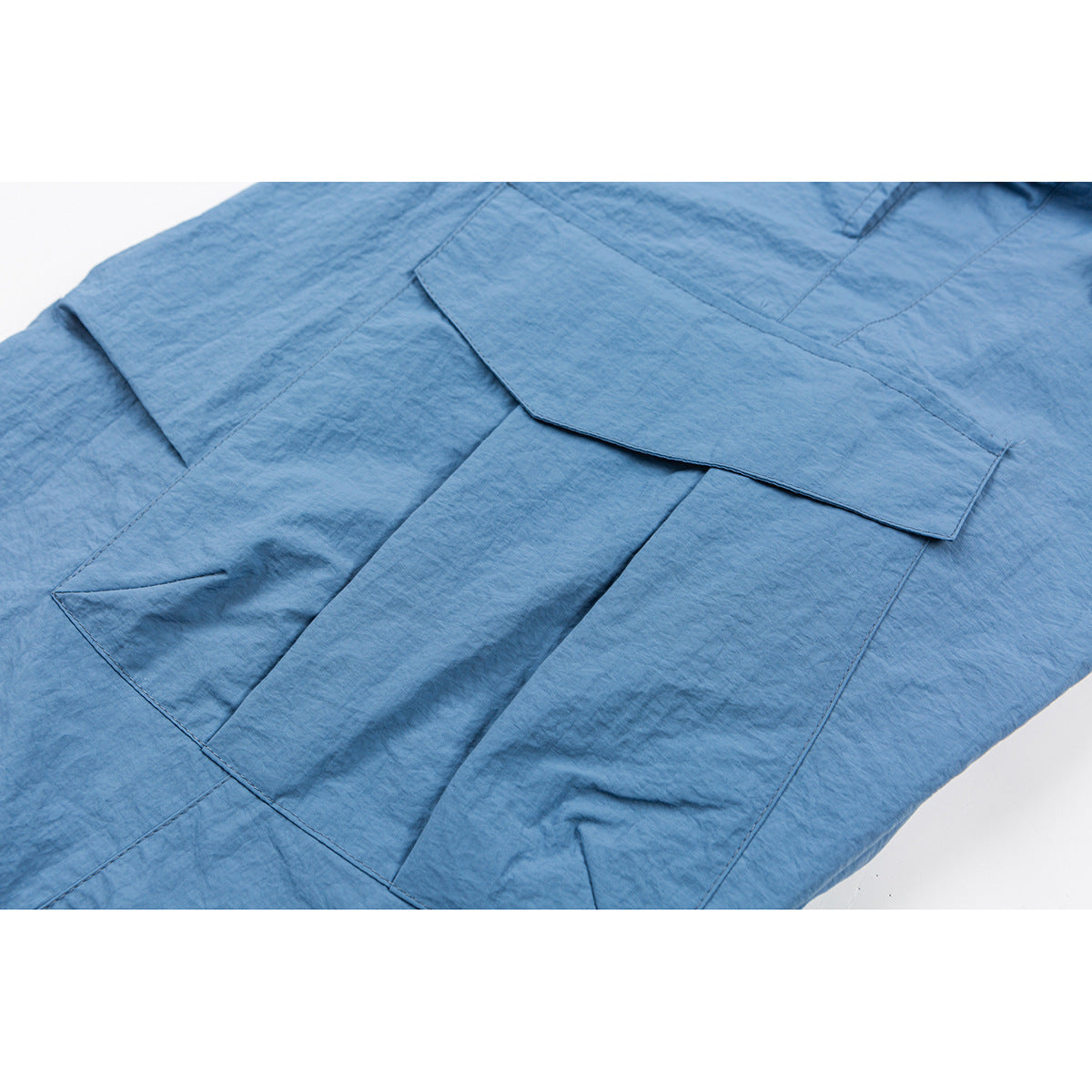Close-up of blue cargo pants showing a large flap pocket and layered panels.