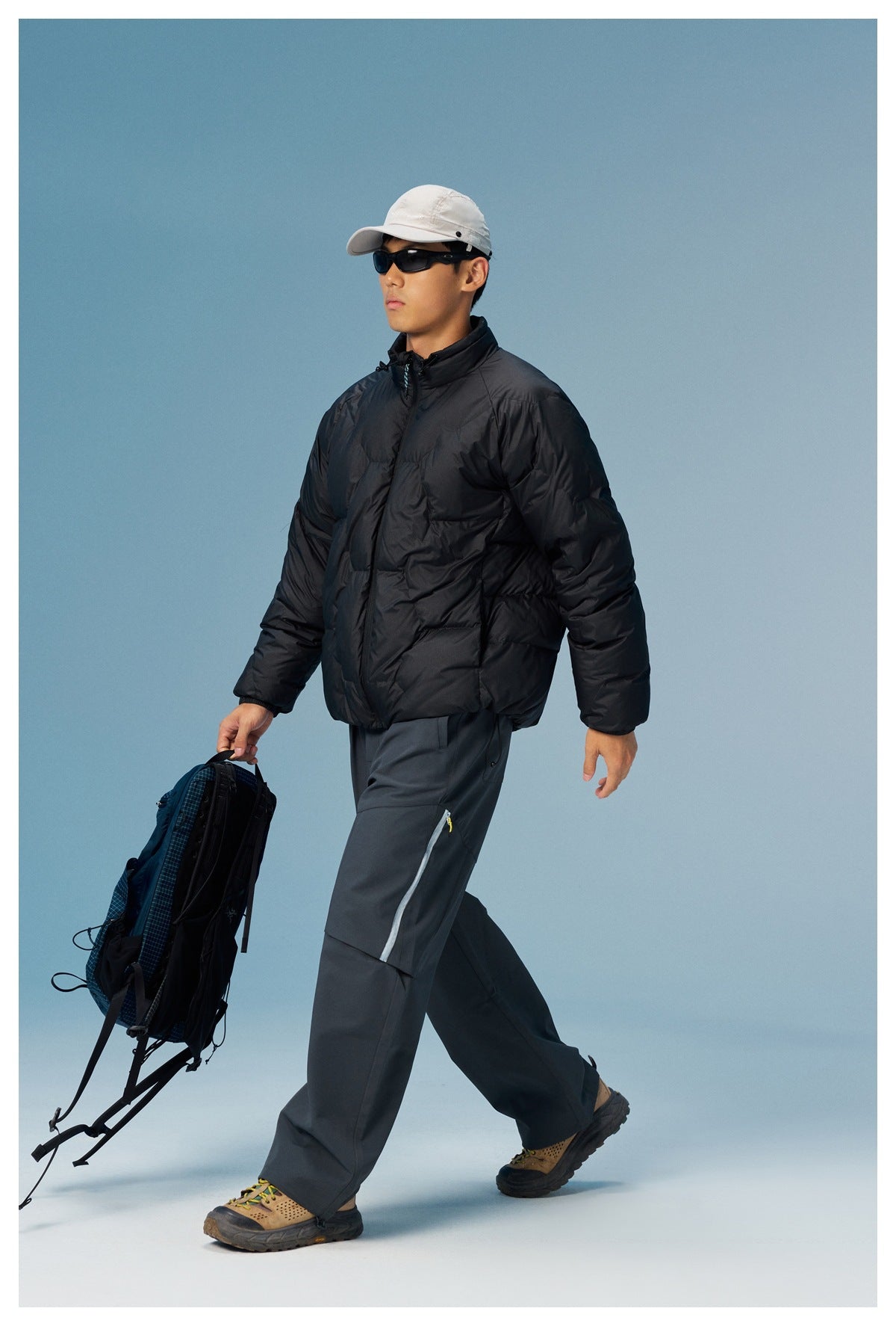 Side view of a model in a black quilted puffer jacket with a relaxed fit, carrying a backpack