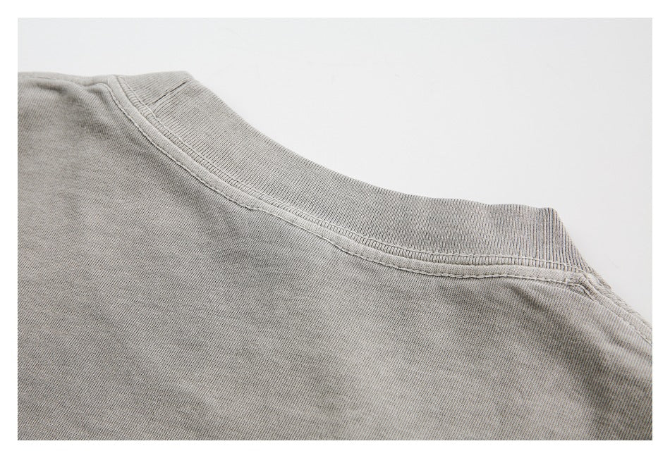 Close-up of the ribbed crew neckline and shoulder seams on a gray garment.