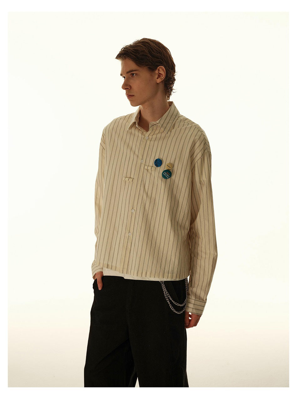 Model in a beige striped button-up shirt with decorative pins, shown at a three-quarter side angle.