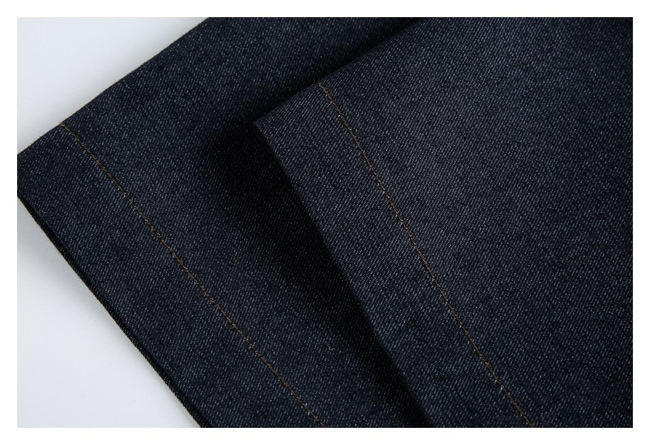 Close-up of overlapping dark indigo denim panels with straight brown topstitching.