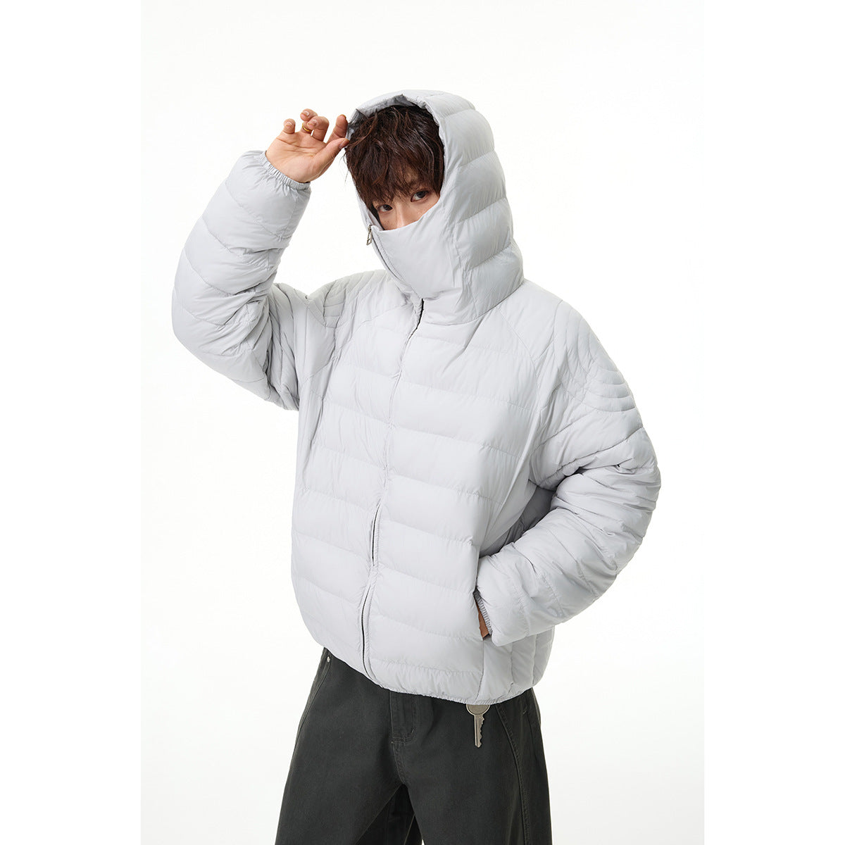 Model wearing a light gray quilted jacket with an oversized hood and high face-covering collar.