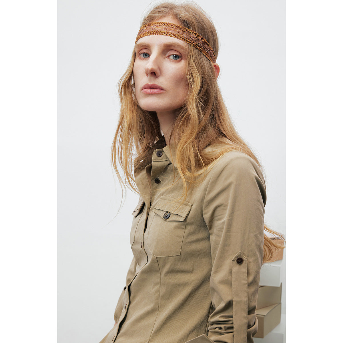 Close view of a model wearing a khaki shirt with a button placket, flap chest pocket, and sleeve tab.