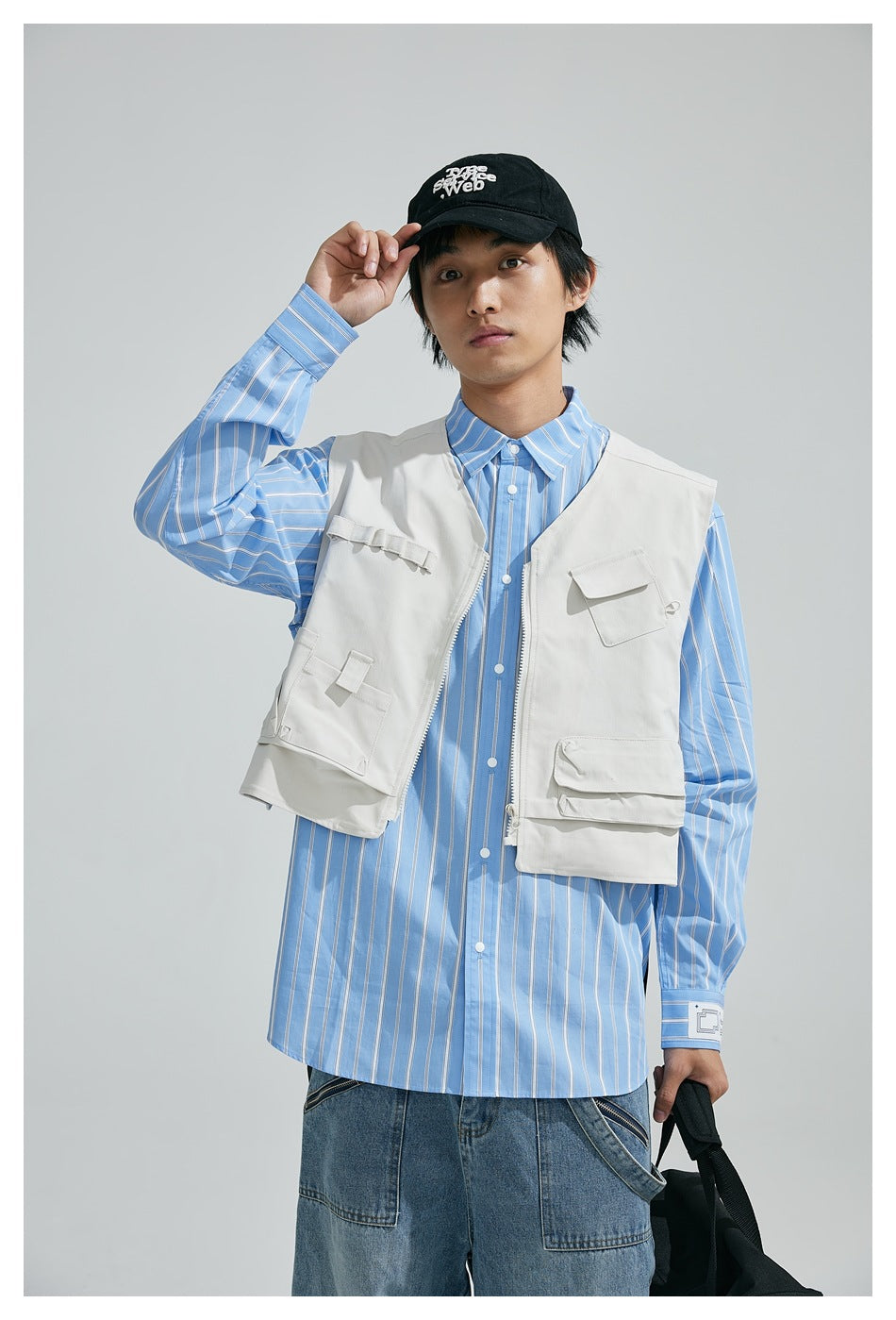 Closer front view of a model wearing a white utility vest over a blue striped shirt.