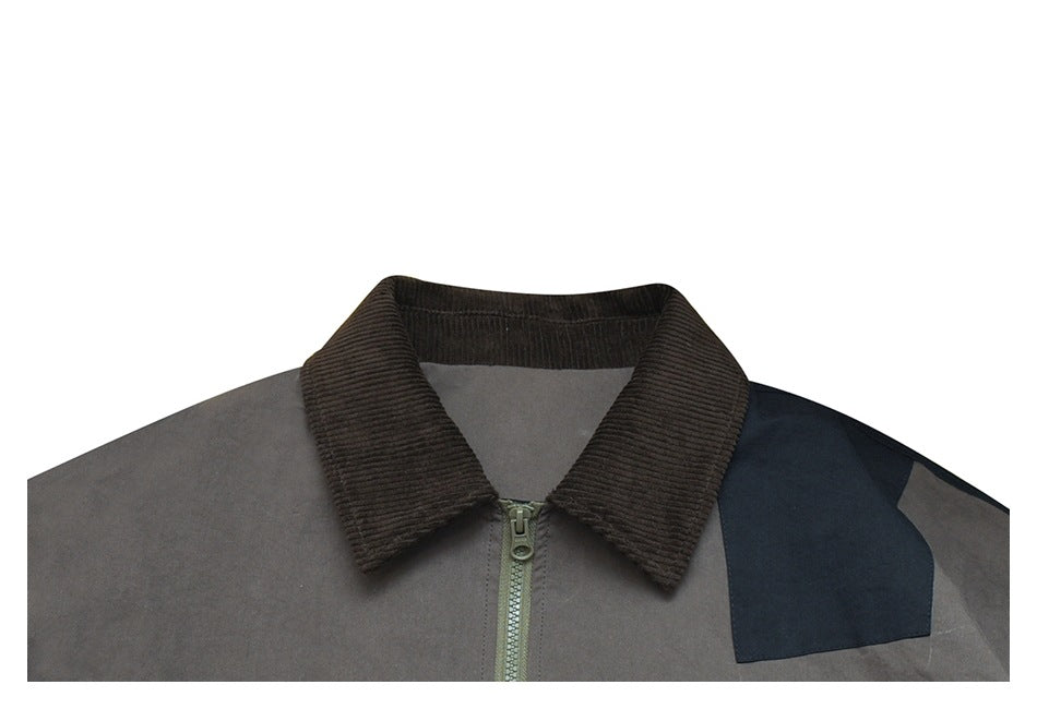 Close-up of a gray jacket front with a brown ribbed collar, center zipper, and navy shoulder panel.