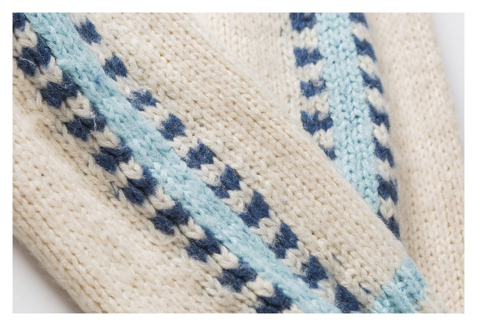 Close-up of cream knit fabric with pale blue stripes and small navy geometric motifs.