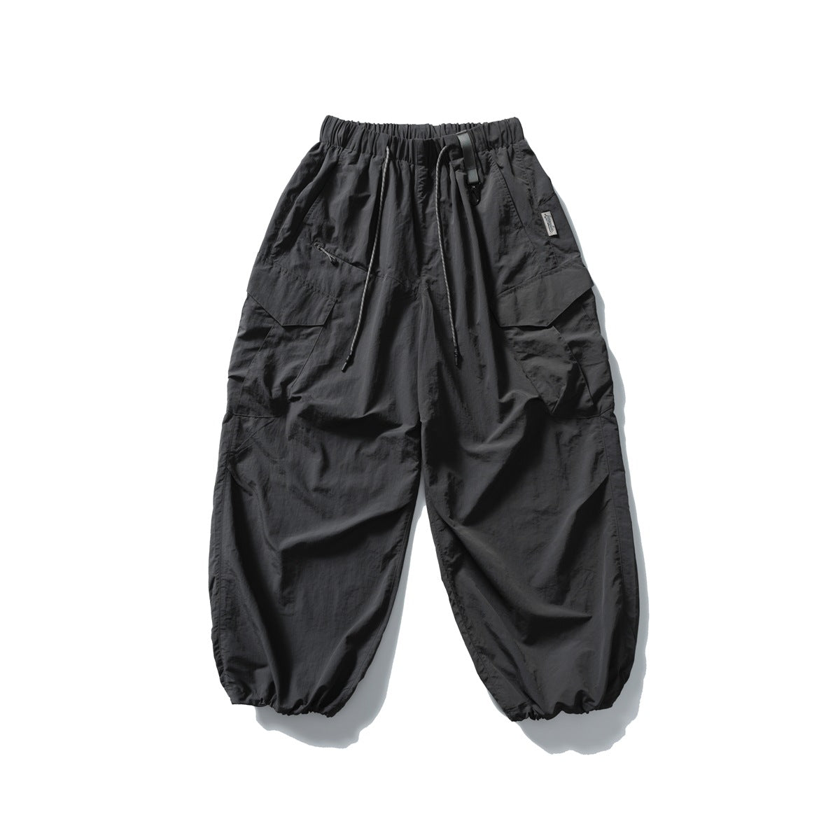 Black oversized cargo pants with an elastic drawstring waist, large flap pockets and gathered ankle cuffs.
