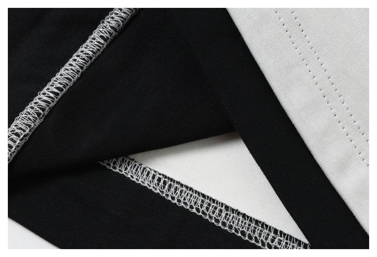 Close-up of black-and-white garment fabric showing contrasting overlock seams and stitching.