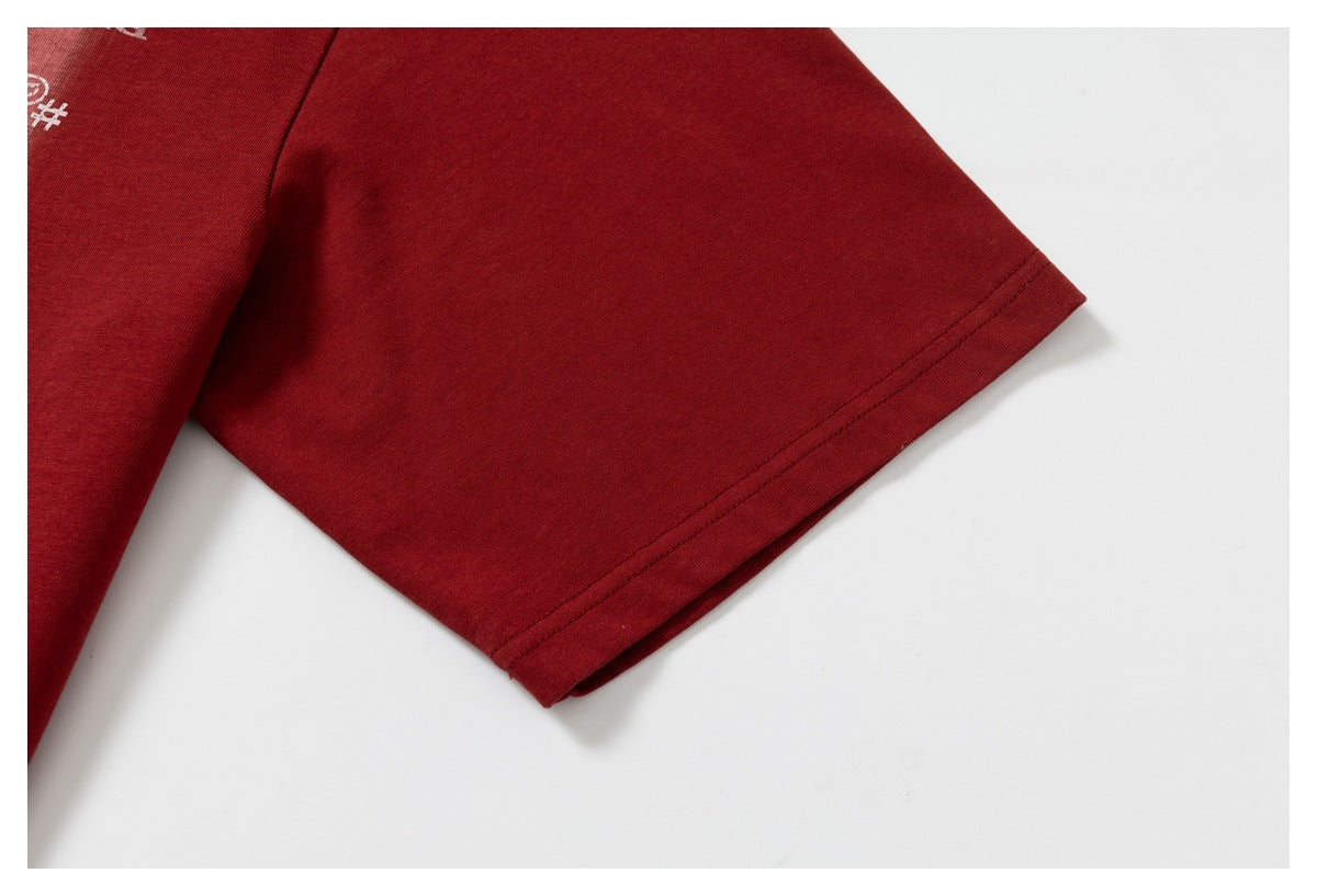 Close-up of a deep red T-shirt sleeve and hem stitching, with part of a white print visible.