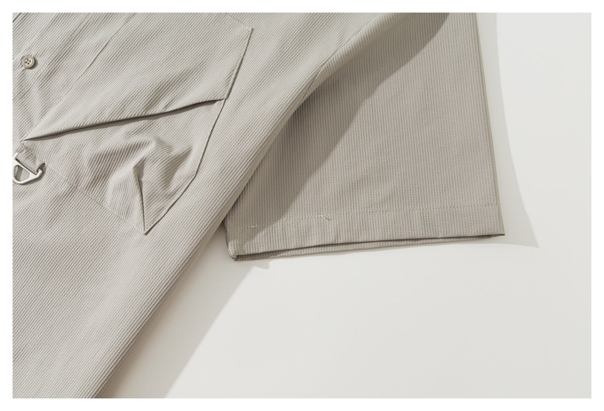 Close-up of the light taupe shirt’s short sleeve hem and part of its flap chest pocket.