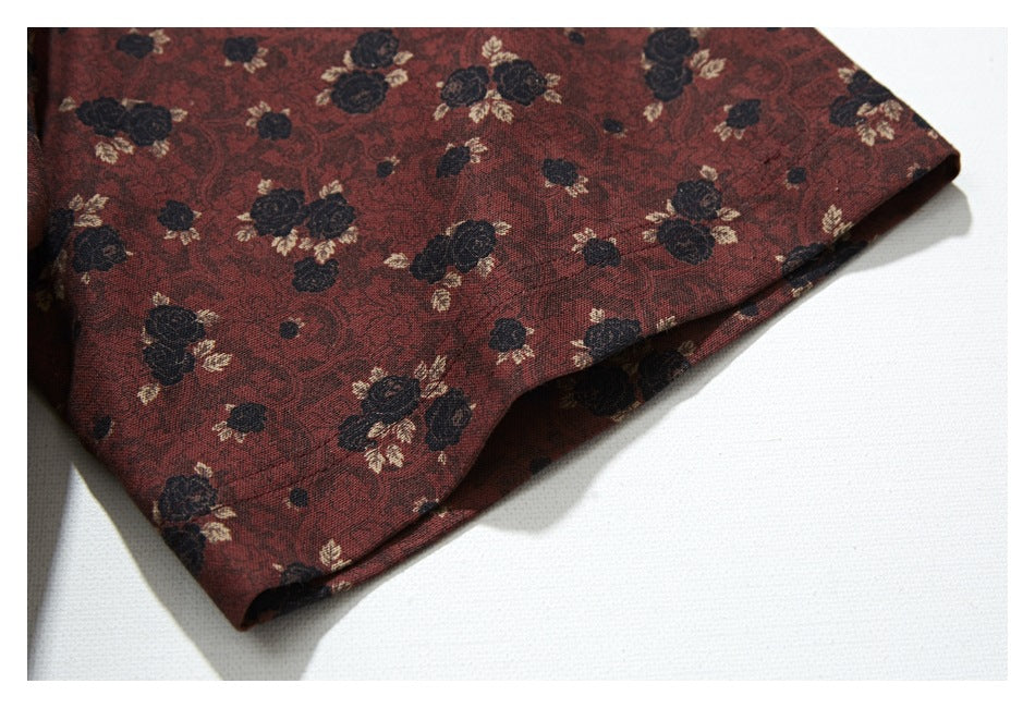Close-up of the folded edge of a reddish-brown floral garment against a white background.