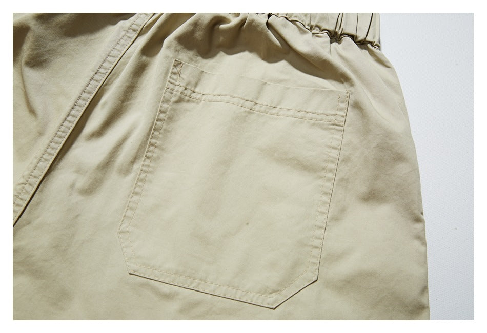 Close-up of a large stitched rear pocket on beige trousers.